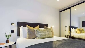A modern hotel room with a large bed, a round side table, and a mirror. - Light-filled Maida Vale Mews Retreat (Greater London)
