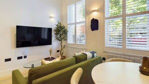 Un salon moderne avec un téléviseur à écran plat, un canapé vert et une table de salle à manger ronde.