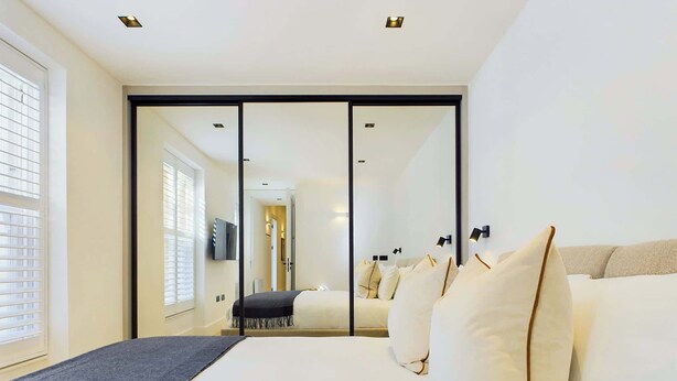 Une chambre d’hôtel moderne dotée d’un grand lit, d’un dressing et donnant sur le couloir.