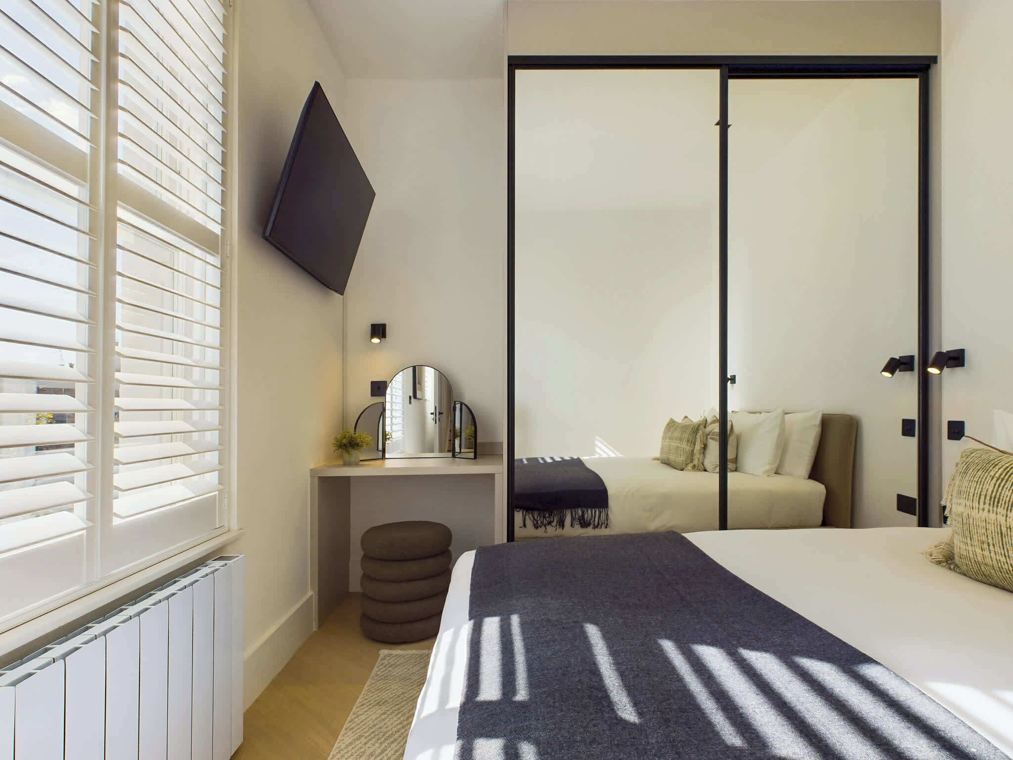 Un dormitorio moderno con cama, mesita de noche, espejo y armario con puerta corredera.