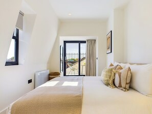 A bedroom with a large bed, a window, a balcony, and a view of the outside. - Penthouse Apartment with Balcony in Maida Vale (Greater London)