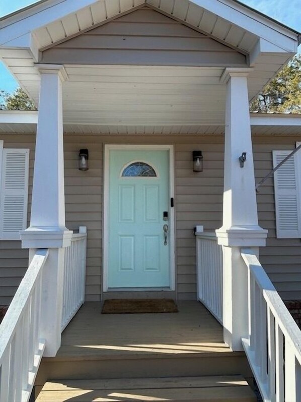A house with a light blue door, white columns, and a covered porch with steps leading to the entrance.