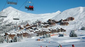 A ski resort with multiple chalet-style buildings, ski lifts, and a snowy landscape. - Ski-in/ski-out & foot of the slopes, 4th floor, view ski slopes, balcony, tv, 29m², La Plagne (La Plagne)