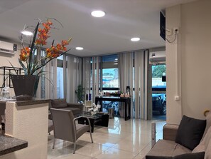 A modern living room with a sofa, a coffee table, and a potted plant. - Executivo Prime Hotel (Teresina)