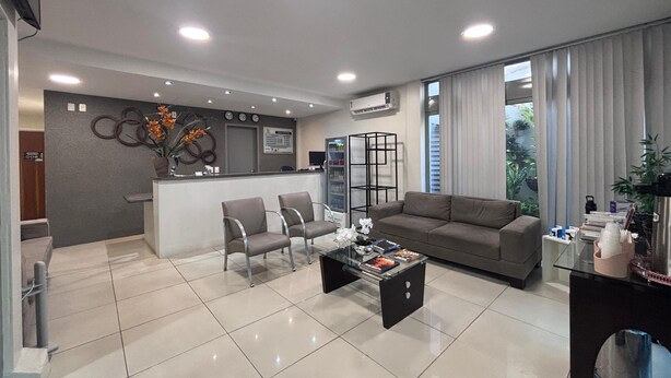 Una sala de estar moderna con un sofá, dos sillones, una mesa de centro y un mostrador de recepción.