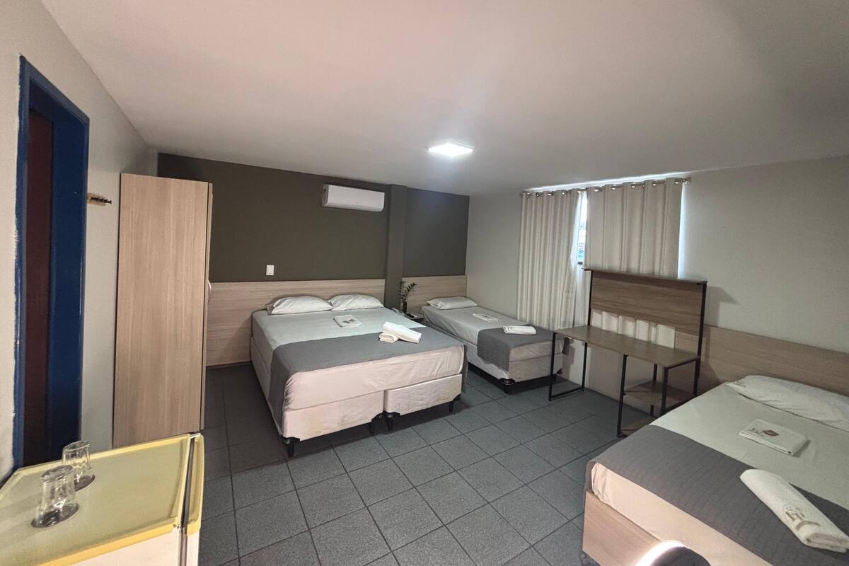 A hotel room with two beds, a desk, and a wardrobe.