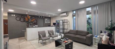A modern living room with a sofa, chairs, a coffee table, and a reception desk.