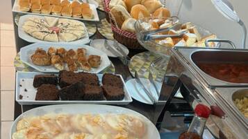 A buffet with various food items including bread, pastries, and desserts.