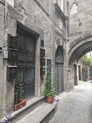 A narrow cobblestone street with a stone building featuring ornate black metal doors and mailboxes. - Enchanting suite in San Pellegrino, in the heart of Viterbo's historic center (Viterbo)