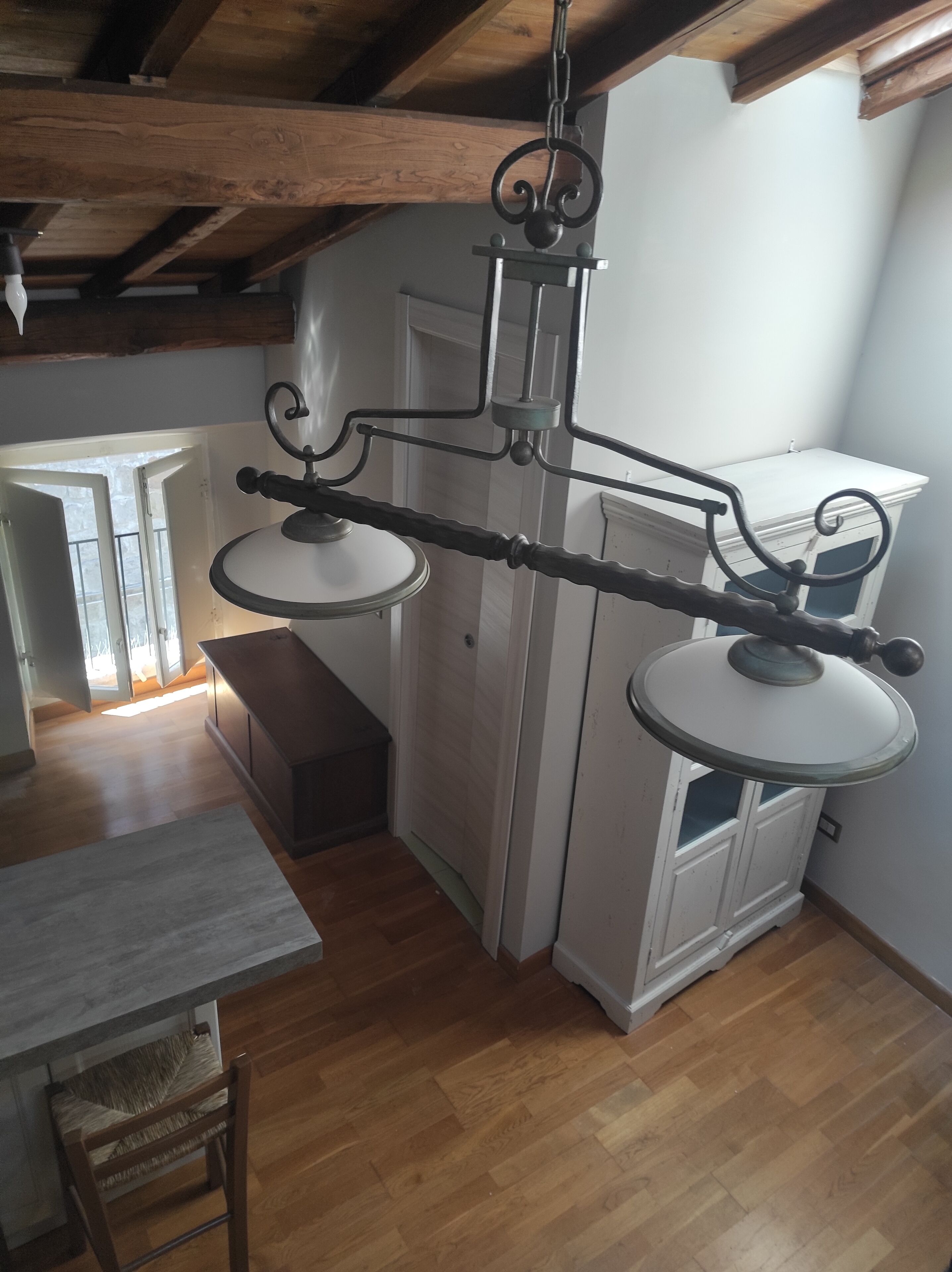 Une cuisine avec des poutres en bois, un luminaire suspendu et un meuble blanc.