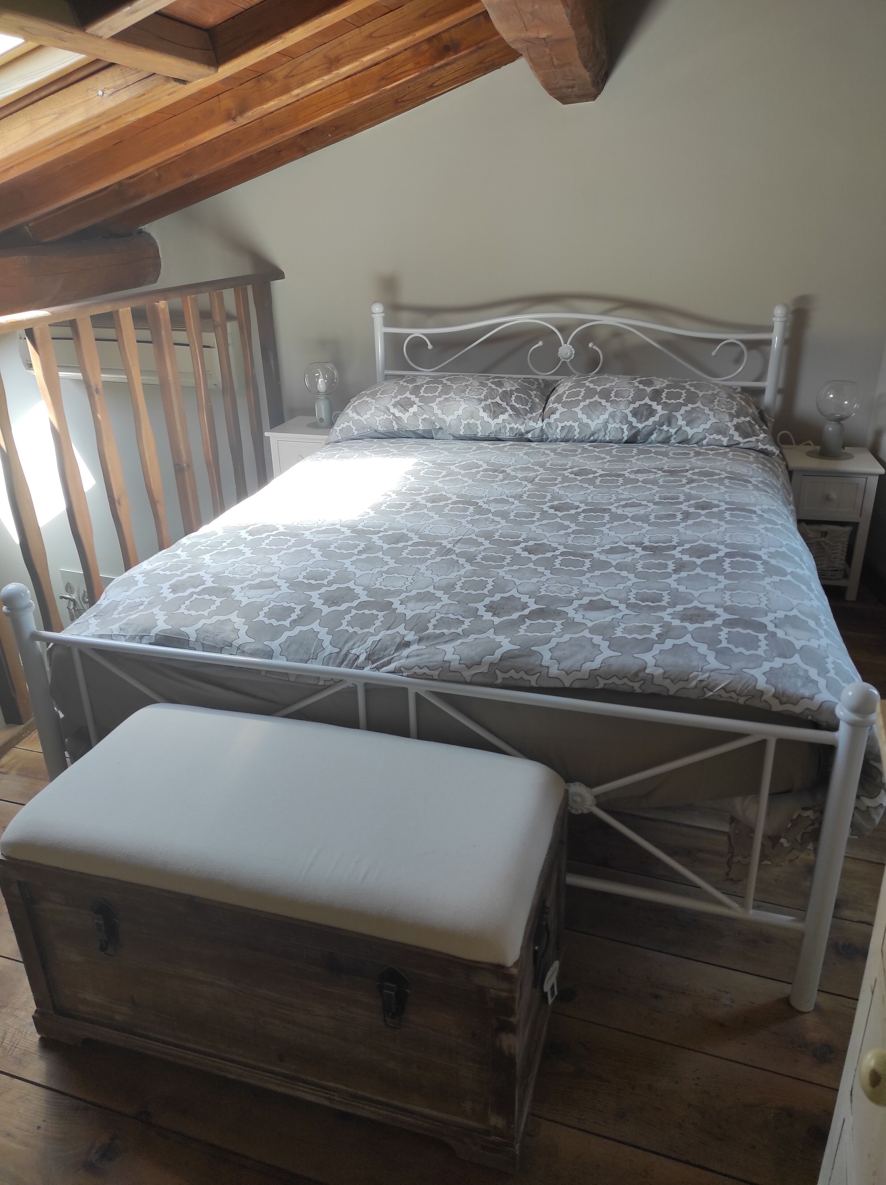 Une chambre à coucher avec un lit, un banc en bois et une table de chevet avec une lampe.