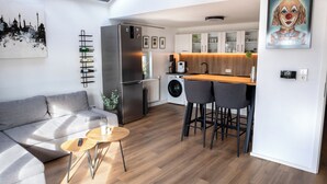 A modern living room with a sofa, a coffee table, and a small dining area. - Zentral am Stadtwald (Hannover)