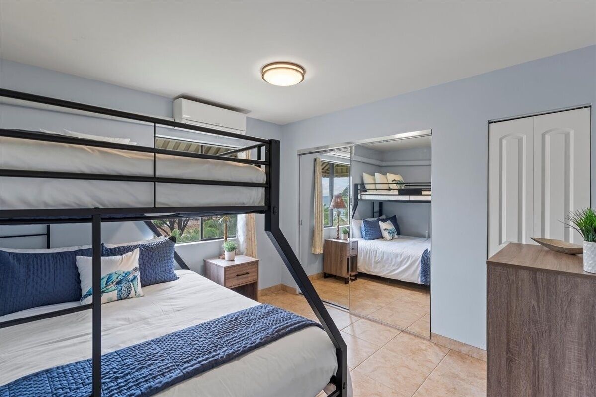 Un dormitorio moderno con literas, una mesita de noche con lámpara y vistas a través de un ventanal.