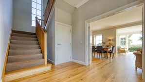 A spacious interior with a wooden staircase, a dining area with a table and chairs, and a view of the outdoors. - Farmhouse Retreat with Large Hot Tub (Bishopton)