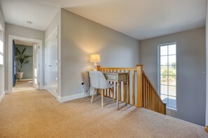 A carpeted hallway with a staircase leading to a room with a window.