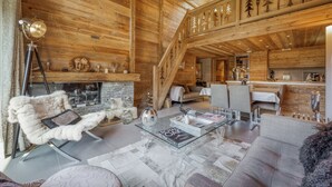A wooden interior with a glass coffee table, a fur chair, and a staircase. - Chalet apartment in Megève (Megève)