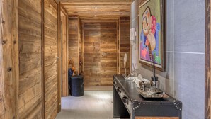 A hallway with wooden walls and a modern black bench with a tray. - Chalet apartment in Megève (Megève)