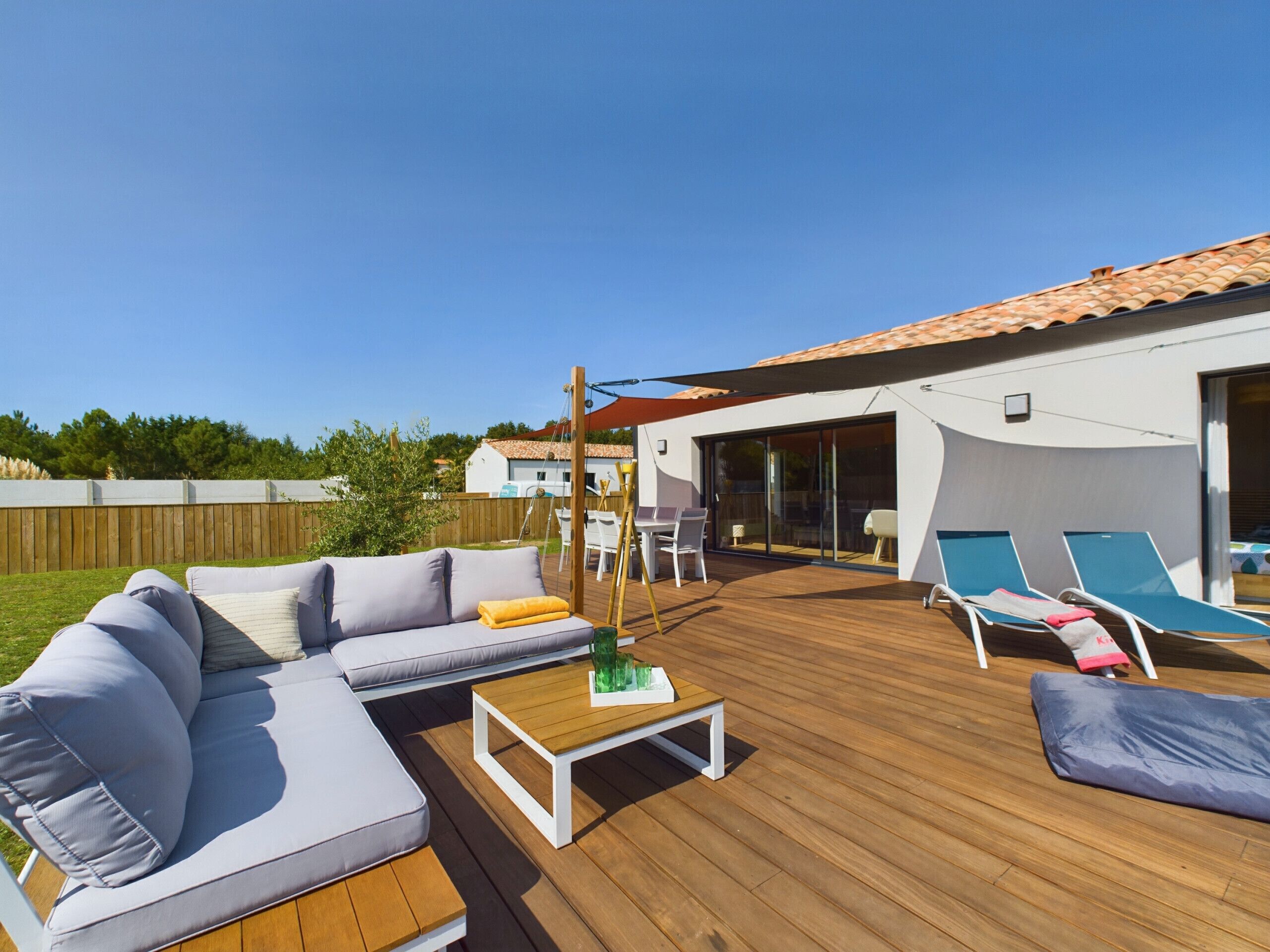 A wooden deck with a sofa, lounge chairs, and a table.