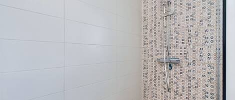 Eine Dusche mit einer Wand mit Muster und einem Fliesenboden.