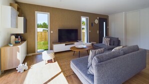 A modern living room with a grey sofa, a flat-screen TV, and a wooden cabinet. - House for 7 with a pool (6 adults maximum) (Saint-Hilaire-de-Riez)