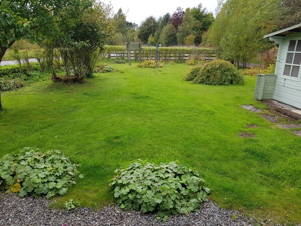Un jardin bien entretenu, avec une variété de plantes et un petit abri de jardin.