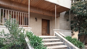Un escalier en pierre menant à une porte en bois, le tout entouré de verdure.