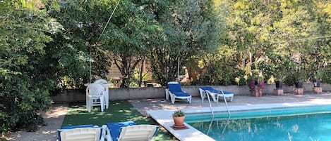A poolside area with lounge chairs, a small table, and a potted plant.