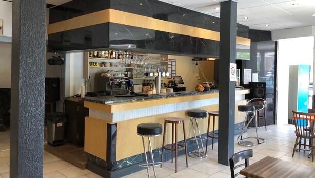 A bar area with a counter, stools, and a seating area with tables and chairs. - Hôtel de la Gare (Périgueux)