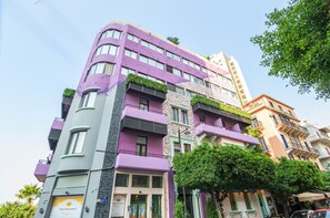 Un immeuble à plusieurs étages doté de balcons, présentant un mélange de styles architecturaux, et surplombant un ciel dégagé.