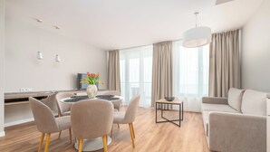 Ein modernes Wohnzimmer mit Sofa, Esstisch, Stühlen und einem Fernseher.