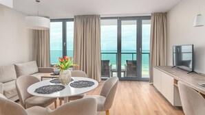 Ein modernes Hotelzimmer mit Balkon, Essbereich und Fernseher.