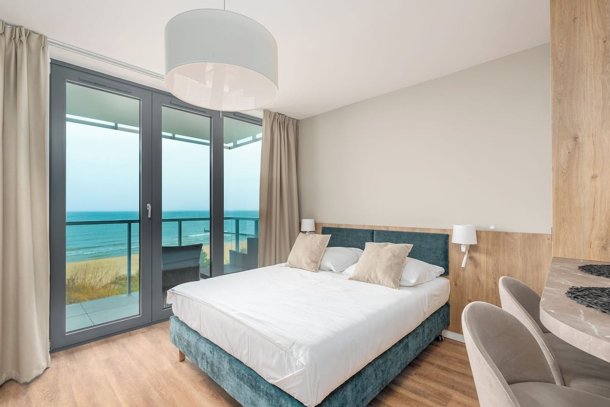 Ein Schlafzimmer mit einem großen Bett, Meerblick und einem Balkon.