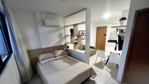 A modern bedroom with a bed, a desk, and a mirror.