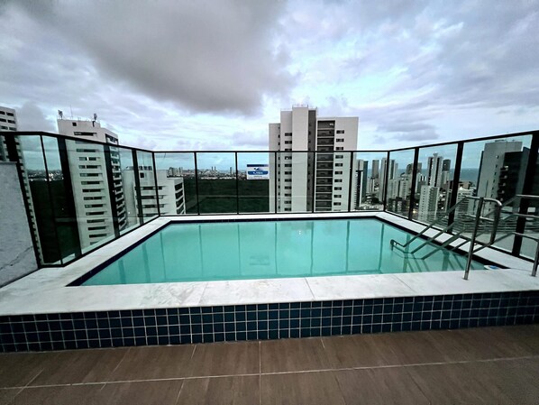 Une piscine sur le toit offrant une vue sur la ville, entourée d’immeubles de grande hauteur.