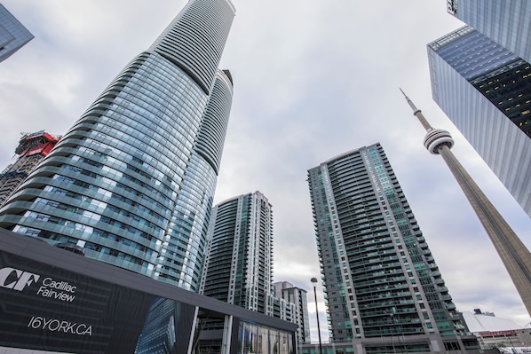 A modern high-rise building with a curved facade and a prominent tower structure in the background.