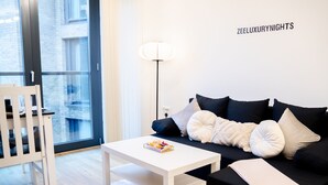 A modern living room with a white sofa, black cushions, a white coffee table, and a floor lamp. - Birmingham City Centre Apartment, Free Parking (Birmingham)