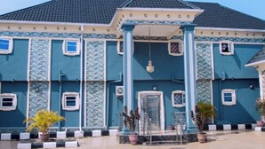 A large building with a tiled roof, multiple windows, and a central entrance with a door.