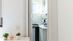 Cozinha moderna com armários brancos, painel de backsplash de tijolo branco e janela que oferece luz natural.