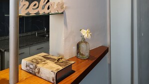 A kitchen with a wooden countertop, a vase with flowers, a shelf with dishes, and a sign that says "relax". - Plaza Independencia Mendoza Sol y Nieve  (Mendoza)