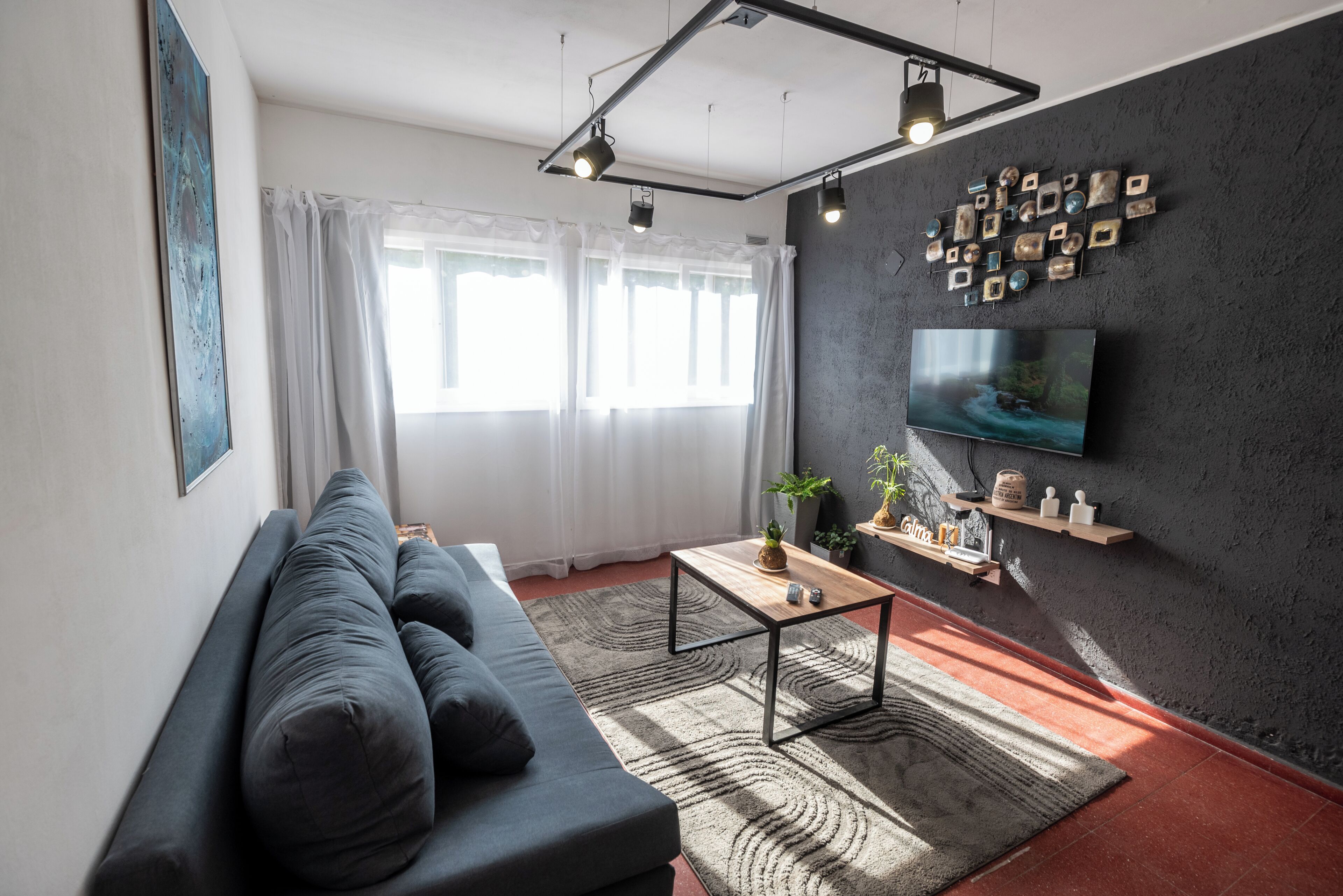 Una sala de estar moderna con un sofá, una mesa de centro y un televisor montado en una pared texturizada.