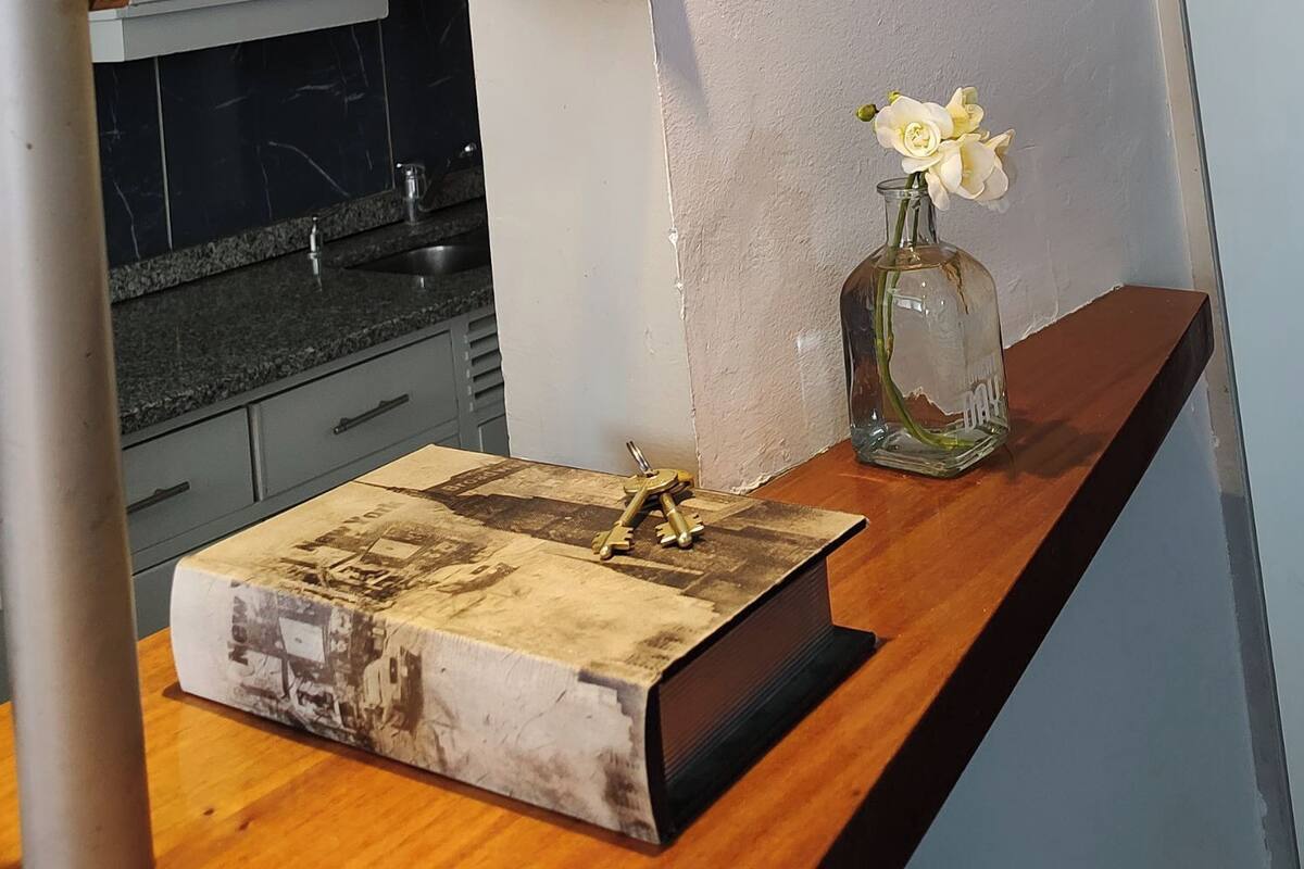 A wooden table with a vintage book, a vase with flowers, and keys.
