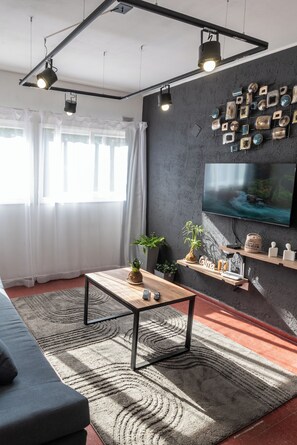 Un soggiorno moderno con una parete scura, una TV a parete e un tavolino in legno.