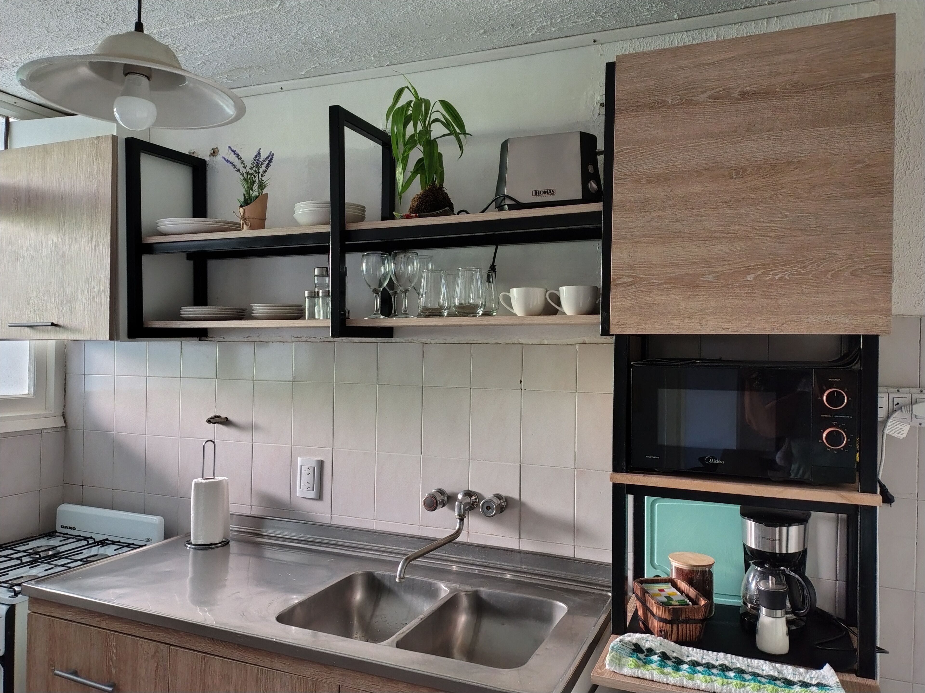 Una cocina moderna con un lavamanos de acero inoxidable, un horno empotrado y una cafetera.