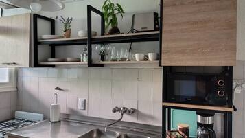 Una cocina moderna con un lavamanos de acero inoxidable, un horno empotrado y una cafetera.