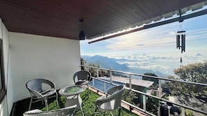 A balcony with wicker furniture and a view of mountains and clouds. - Mount Olympus Lounge (Kodaikanal)