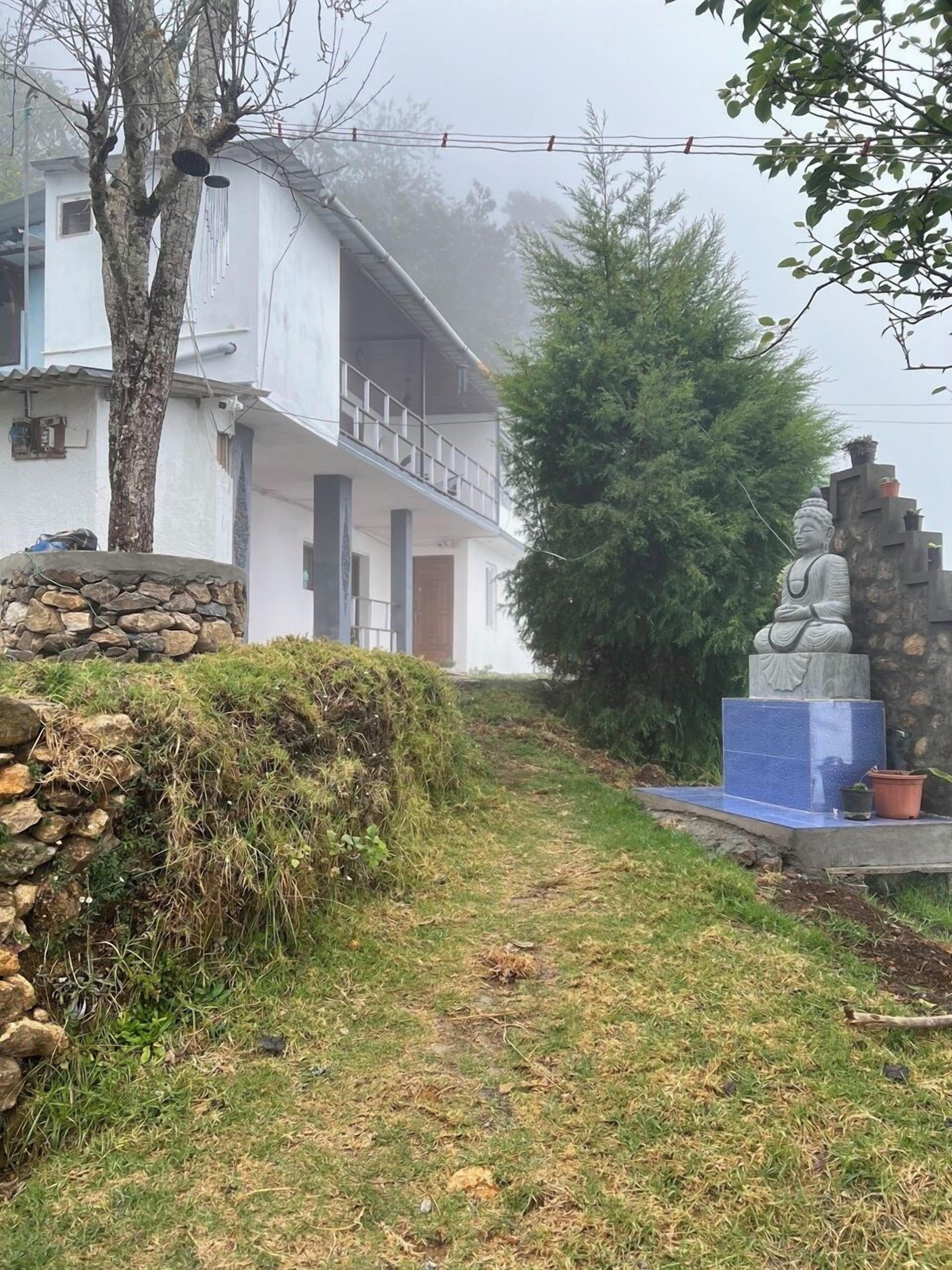 Un edificio con un muro de piedra, una estatua y un árbol.