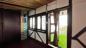 A hallway with a wooden ceiling, a stone wall with a green and white pattern, and a large window with a curtain. - Mount Olympus Lounge (Kodaikanal)