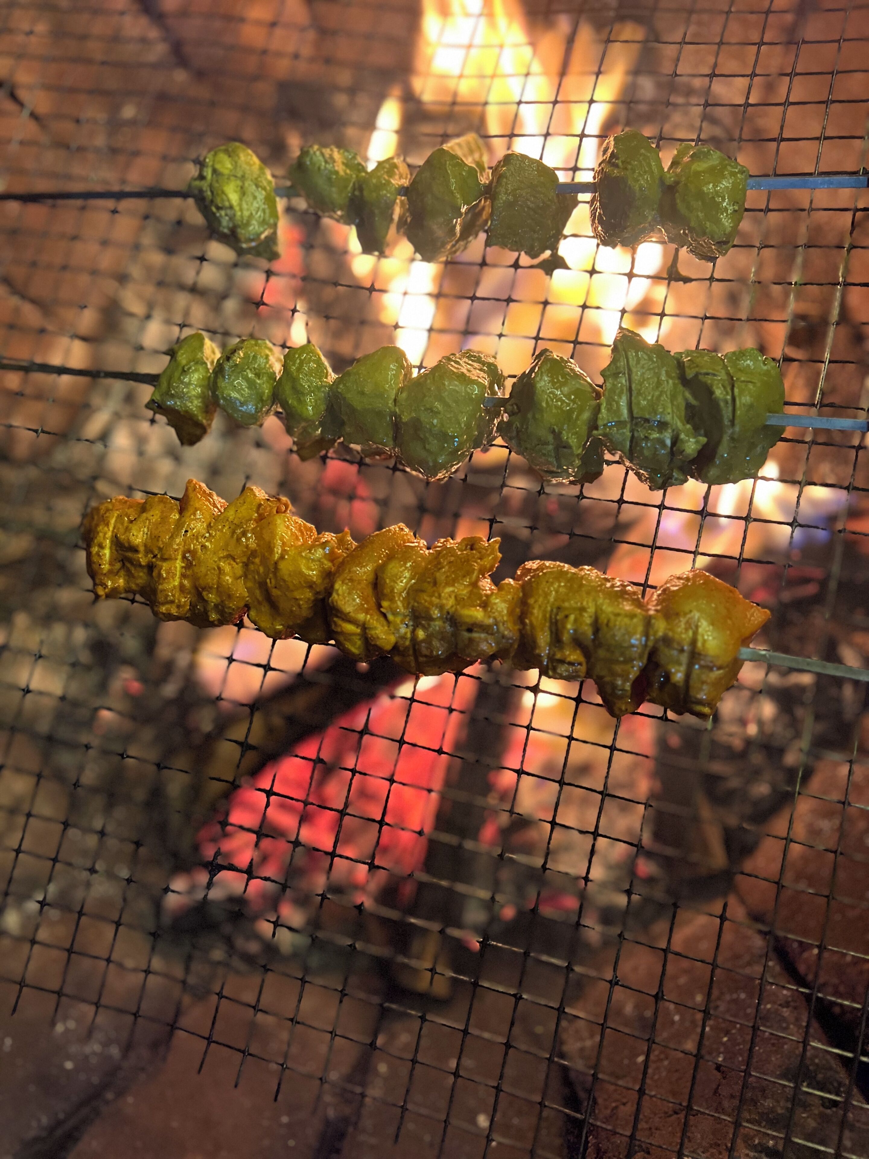Skewers of food being grilled over a fire.