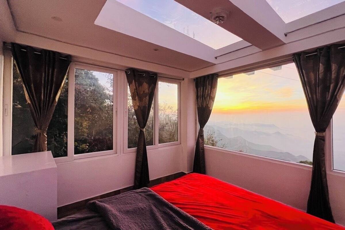 A room with a bed, large windows, and a skylight.