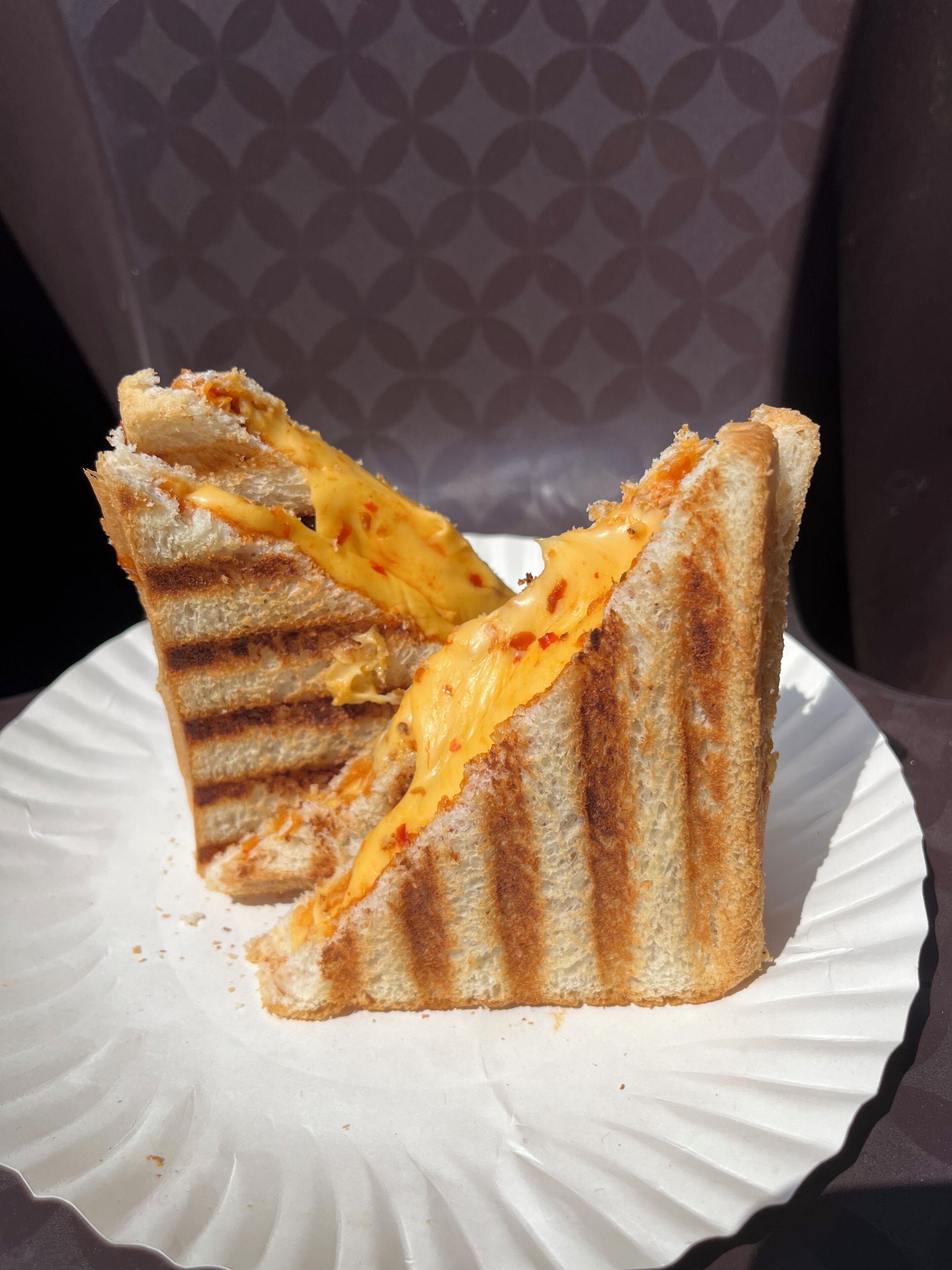Un sándwich de queso a la plancha sobre un plato de papel blanco.